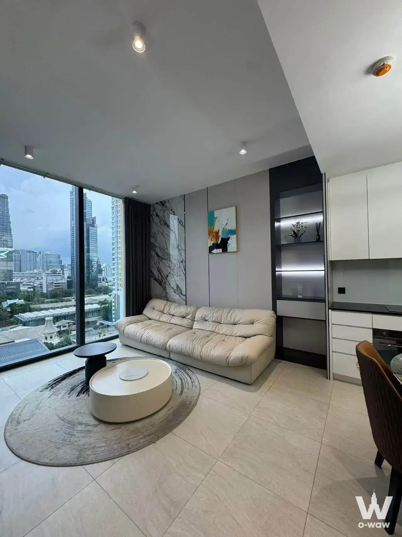 Furnished living area with marble accent wall and skyline view in this 1-bed rental at Tait Sathorn 12