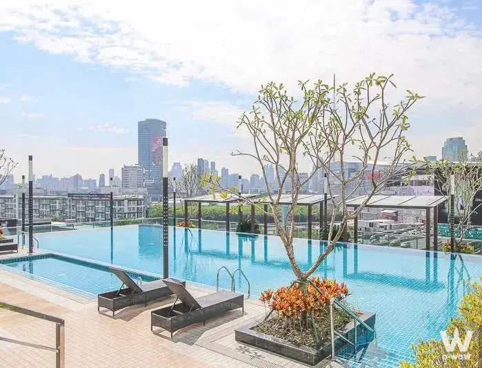 Rooftop infinity pool at TC Green Rama 9 with wicker loungers and city skyline view