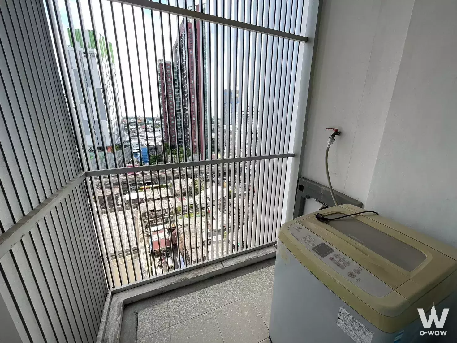 Service balcony in The Bloom Sukhumvit 71 1-bed condo for rent with washing machine, security bars, and distant city views