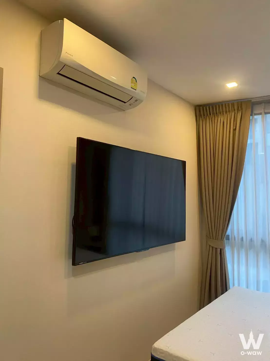 Clean bedroom with wall-mounted TV and beige drapes in The Nest Sukhumvit 71 two-bed condo