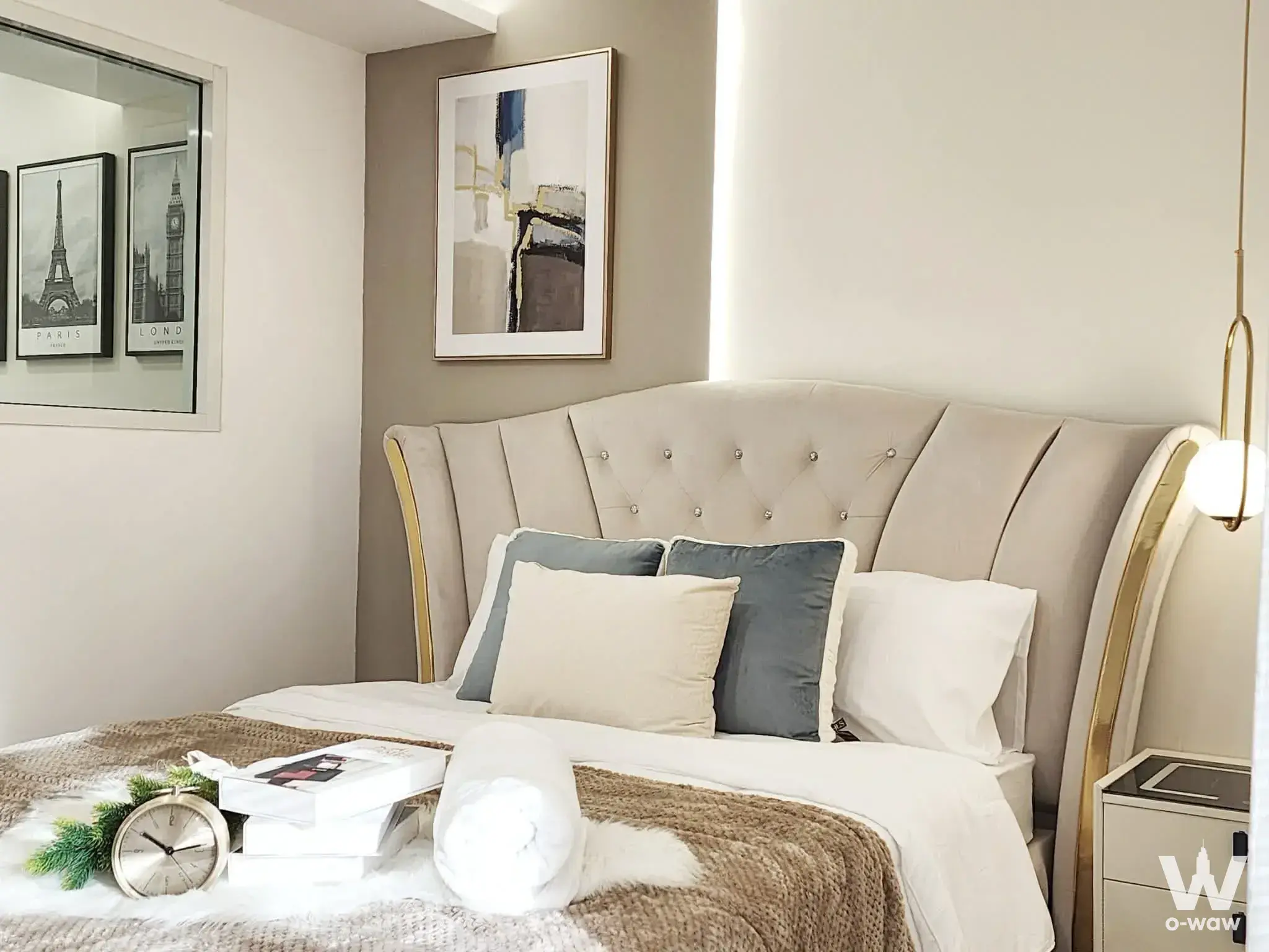 Bedroom in a 1-bed rental at The Parkland Srinakarin Lakeside with beige velvet headboard and gold accent lighting