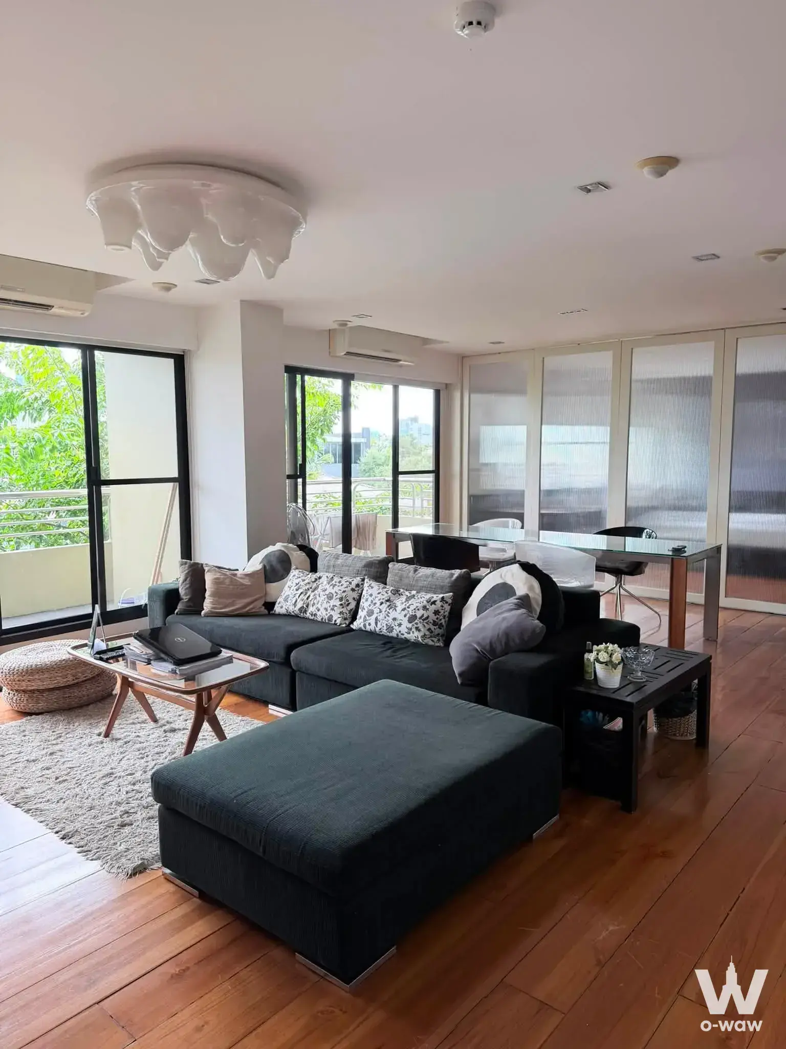 Modern 2-bed condo living room in สุพรีม วิลล์ featuring charcoal sofa and balcony access
