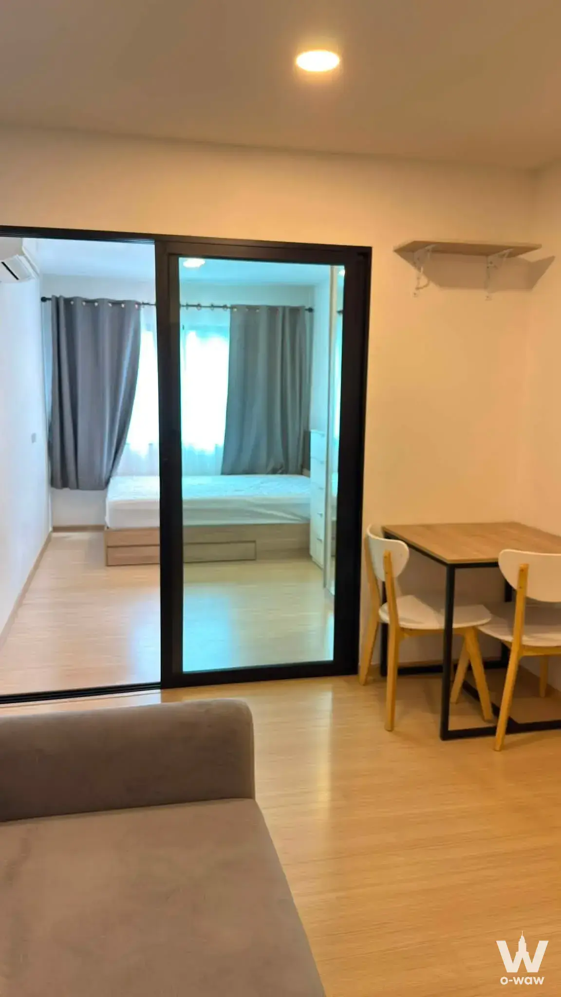 Open-plan 1-bed condo living area in Chewathai Hallmark Ladprao featuring grey sofa and dining set