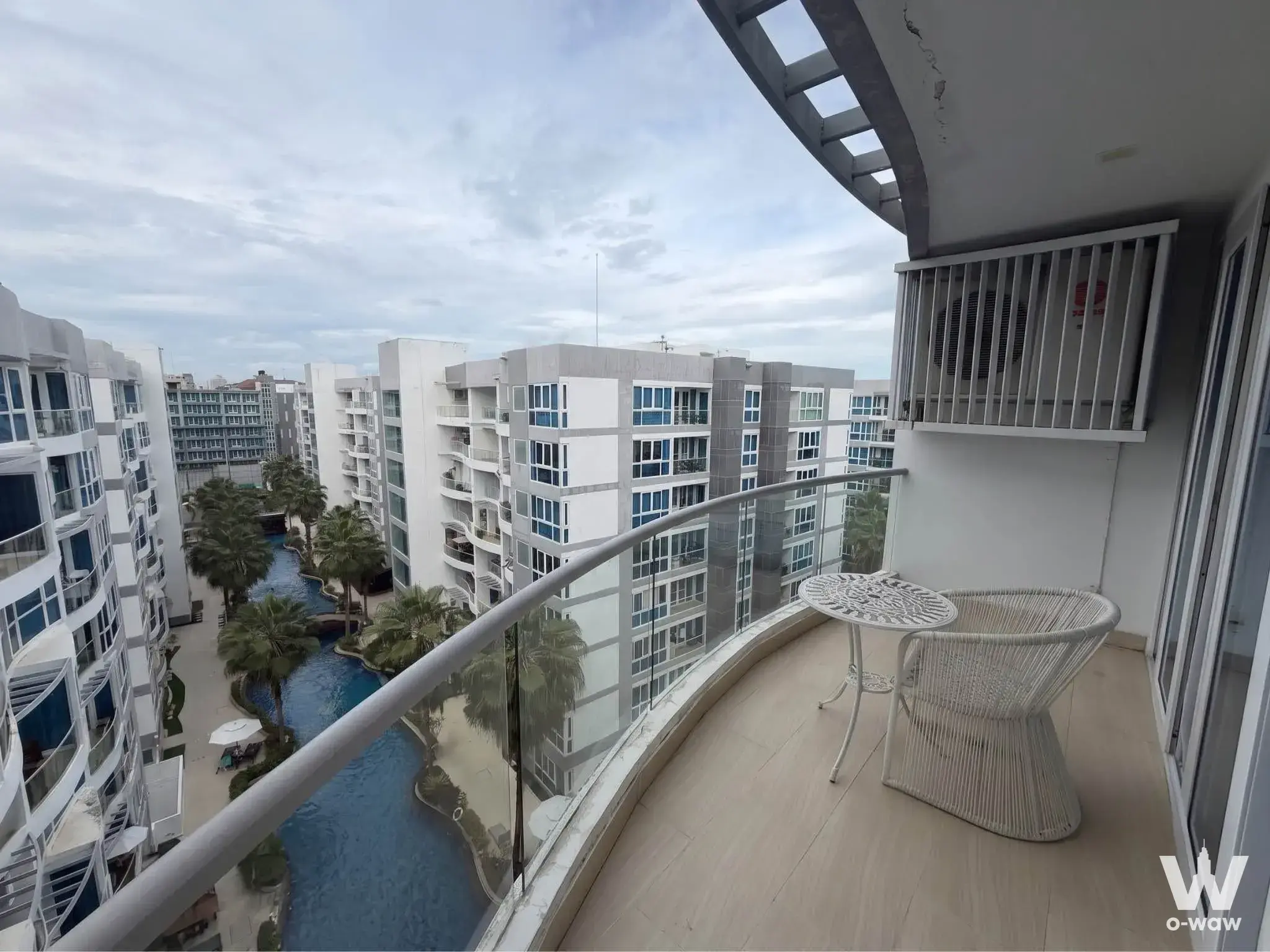 1-bed condo for sale in Grand Avenue Residence showcasing a curved balcony with rattan chair and lagoon pool view