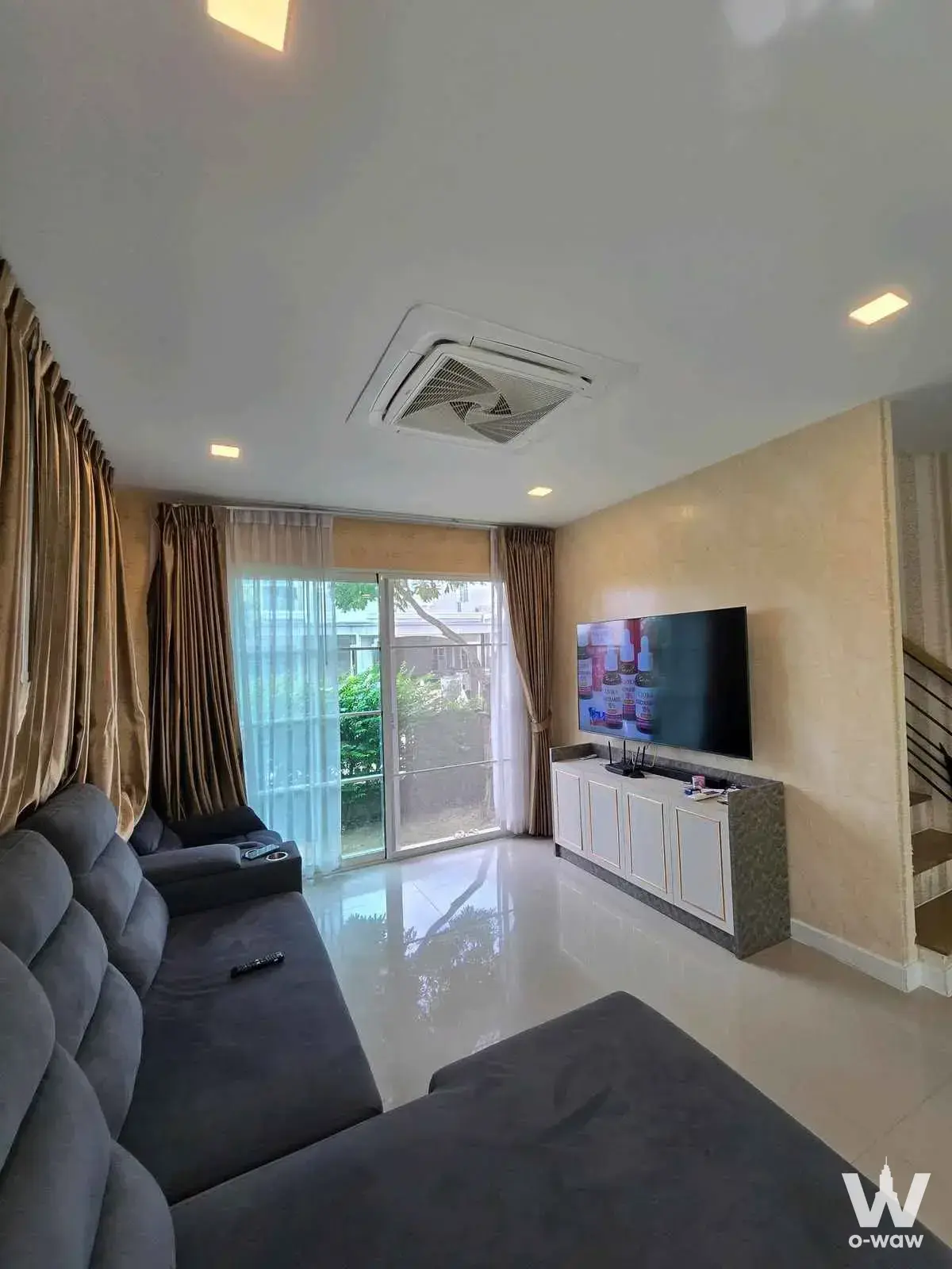 Modern living room in Prestige Future-Rangsit condo with dark-grey sectional sofa and wall-mounted TV
