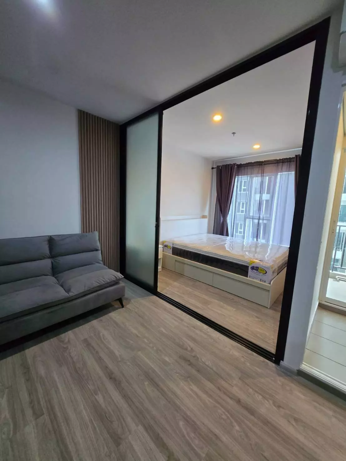 Studio living area with grey sofa and frosted glass partition in Regent Home Bangna