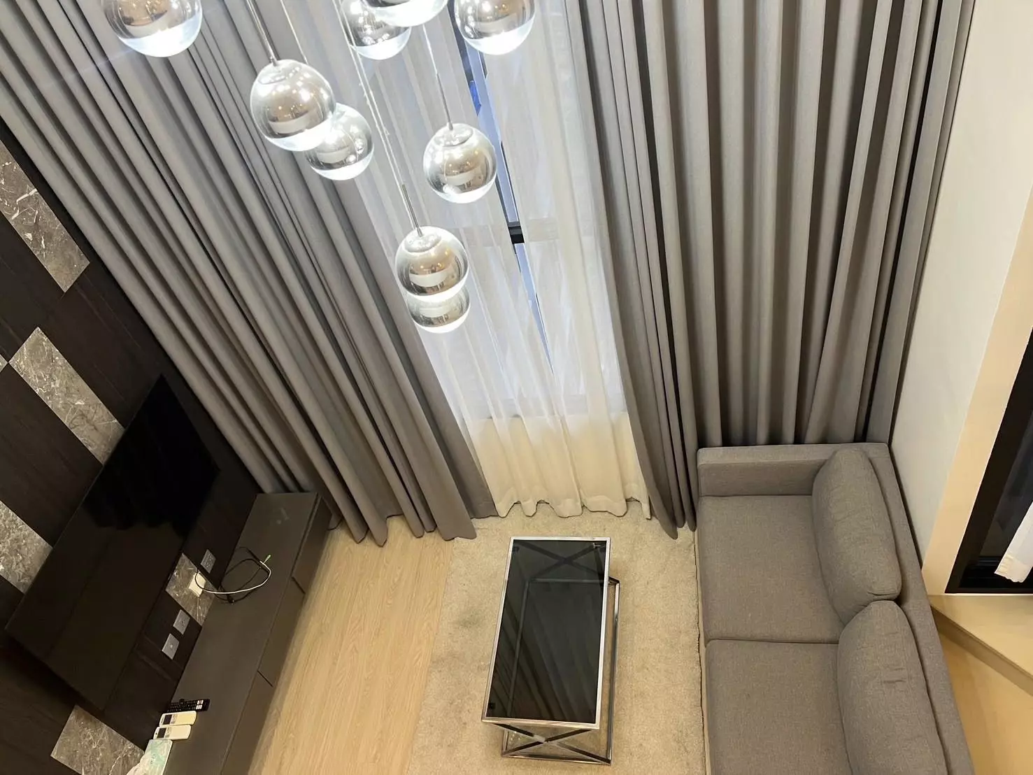 Modern living room in a 1-bed condo at KnightsBridge Prime Sathon with grey sofa and pendant lights