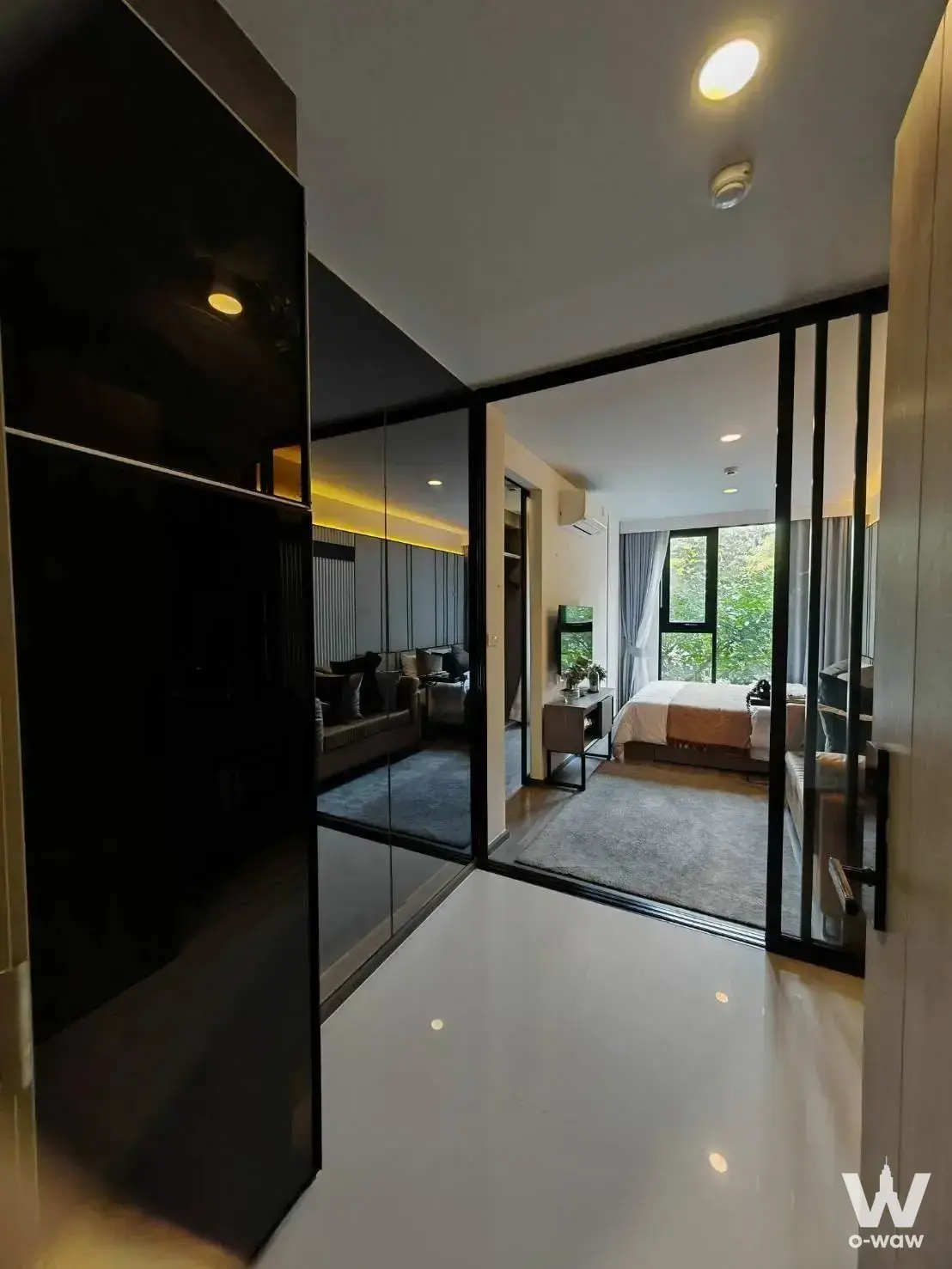 Modern 1-bed condo for rent at The Origin Ladprao 15, featuring black cabinetry and a glass partition separating the bedroom