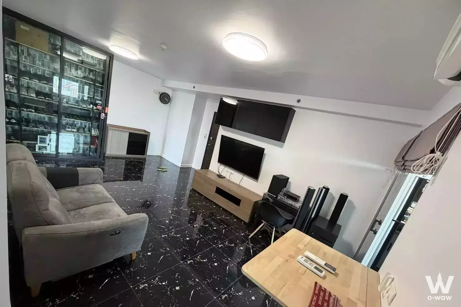 Living room with black marble floor, grey sofa, and sneaker display cabinet in Supalai Park Ekkamai