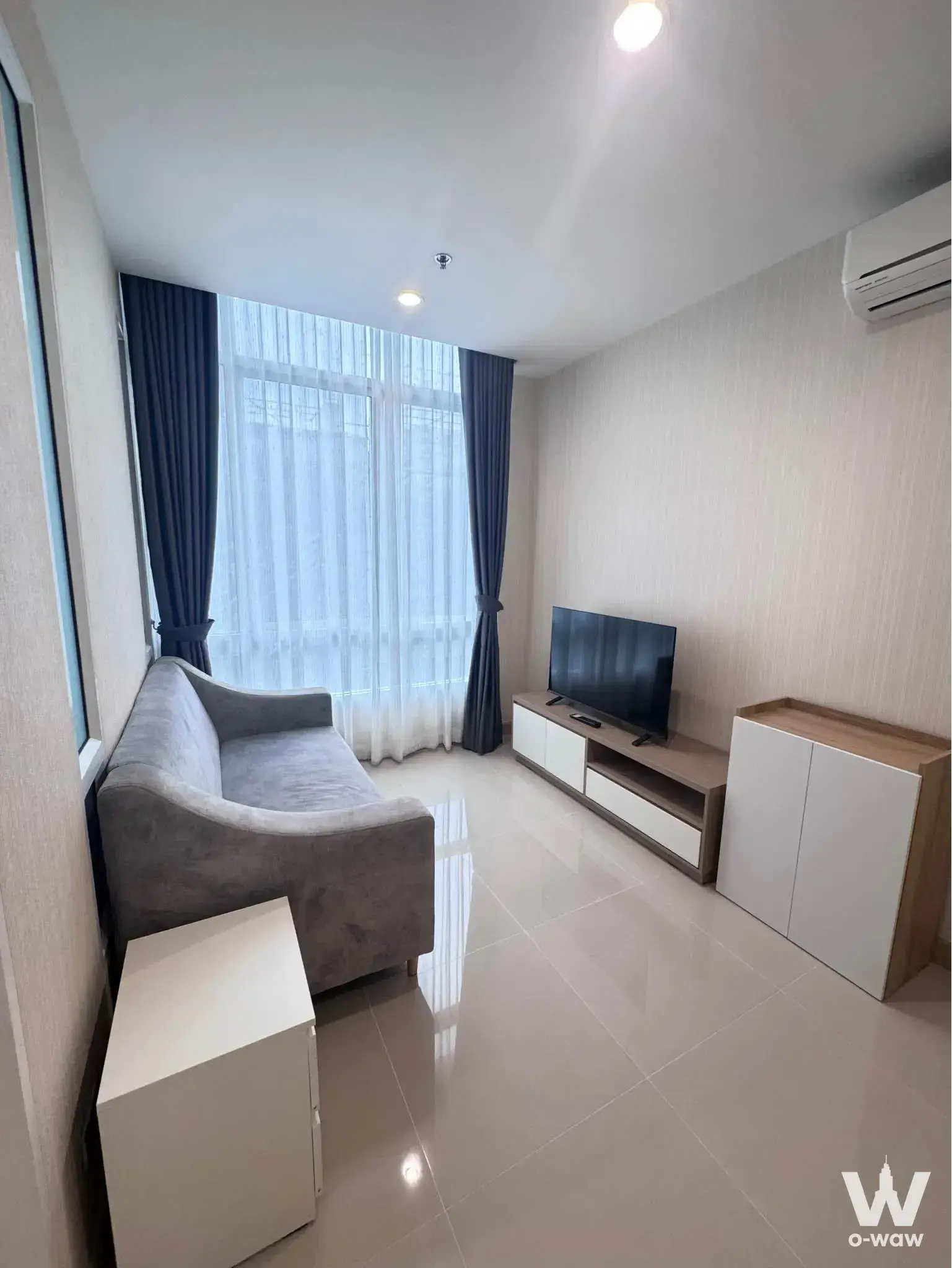 Modern living room with curved sofa and neutral palette in The Sky Sukhumvit 1-bed condo near BTS Udom Suk