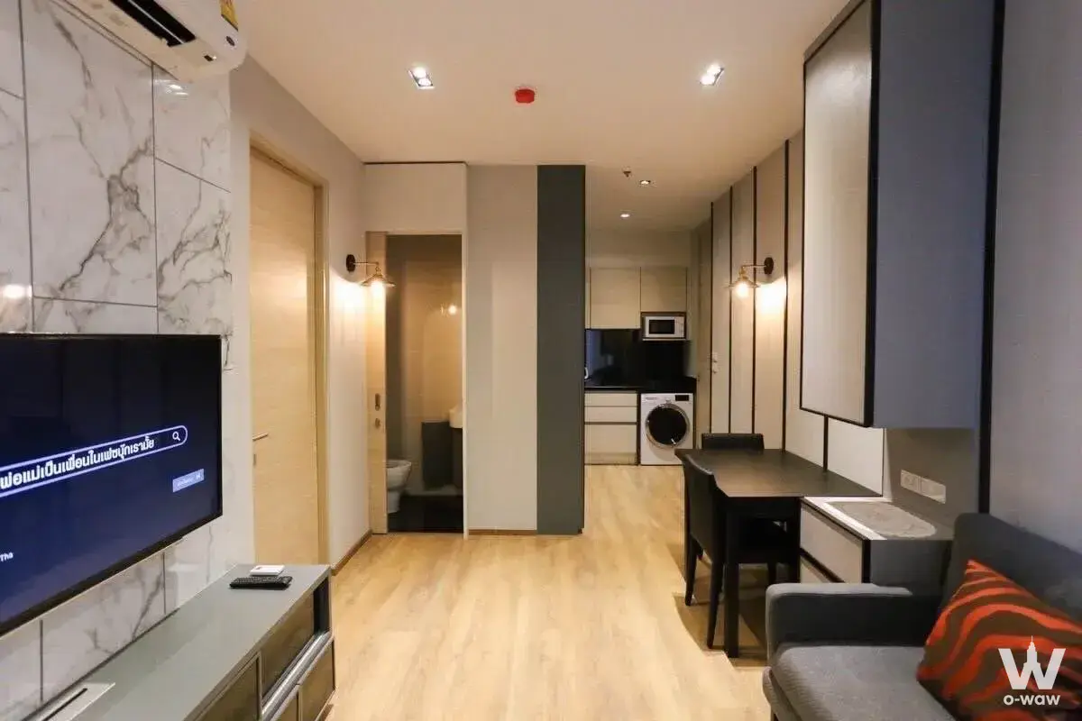 Open-plan studio in Park24 featuring a marble TV wall and compact kitchenette