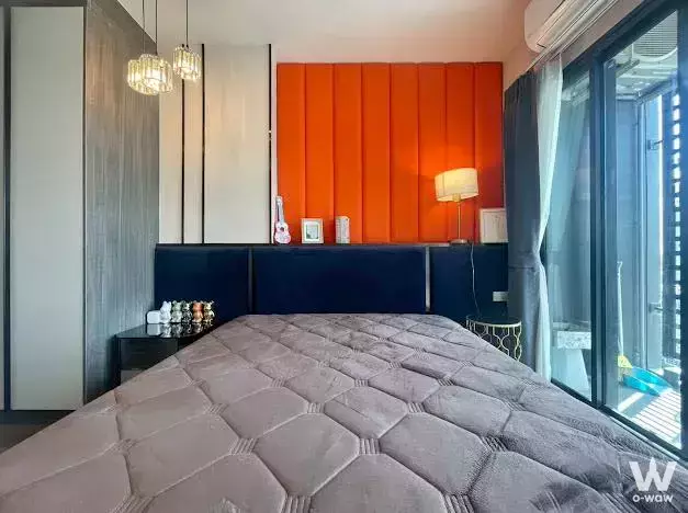 Bright bedroom in a 2-bed IDEO Rama 9 condo with orange tufted headboard and floor-to-ceiling glass door
