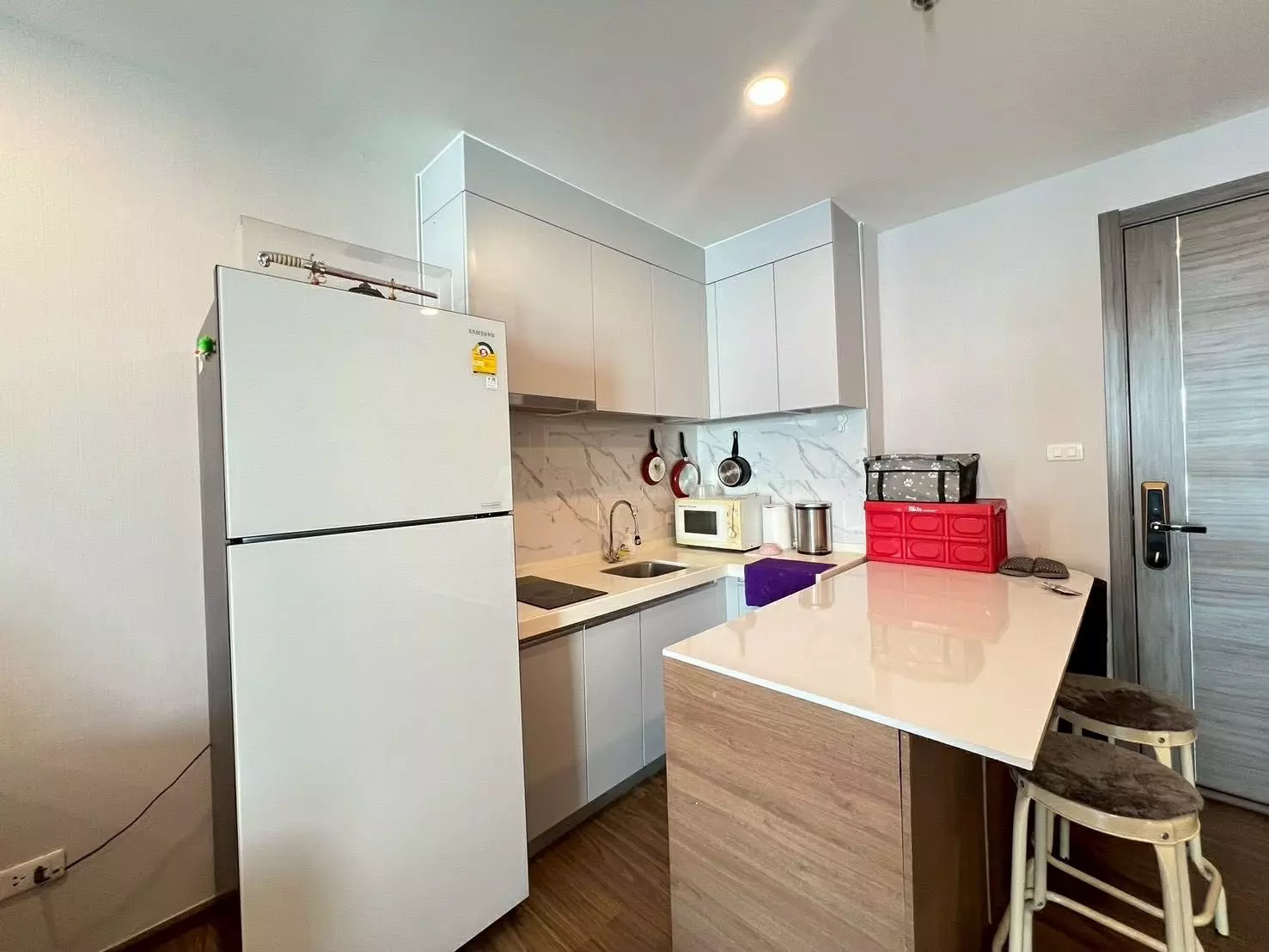 Compact kitchen in Artisan Ratchada with white cabinets, quartz counters, and a central island