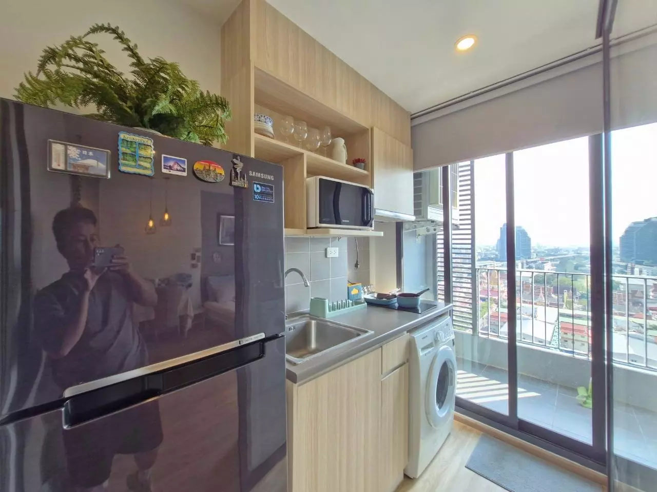 Kitchenette with light wood cabinets and a city view balcony in this 1-bed condo for rent at Ideo O2