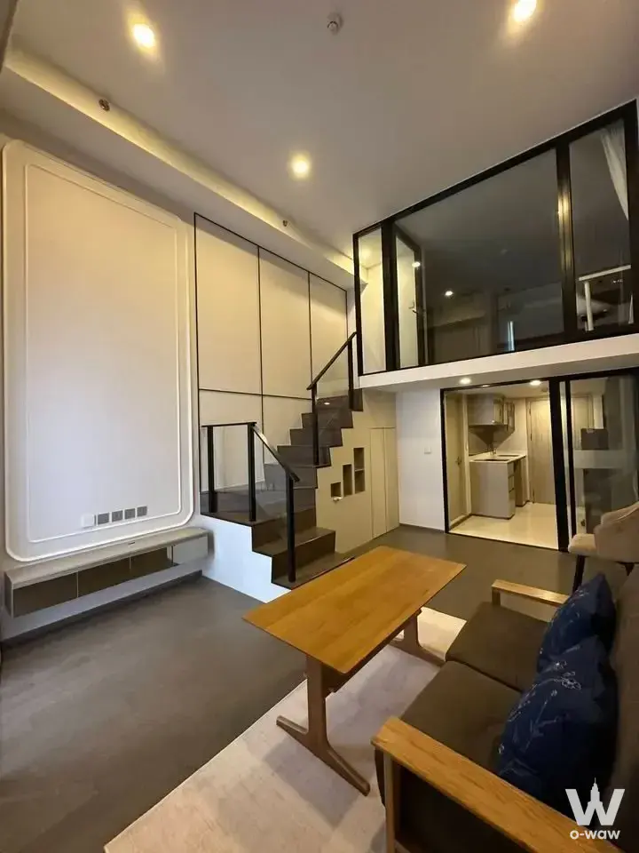 Loft-style living room with mezzanine staircase in Park Origin Ratchathewi