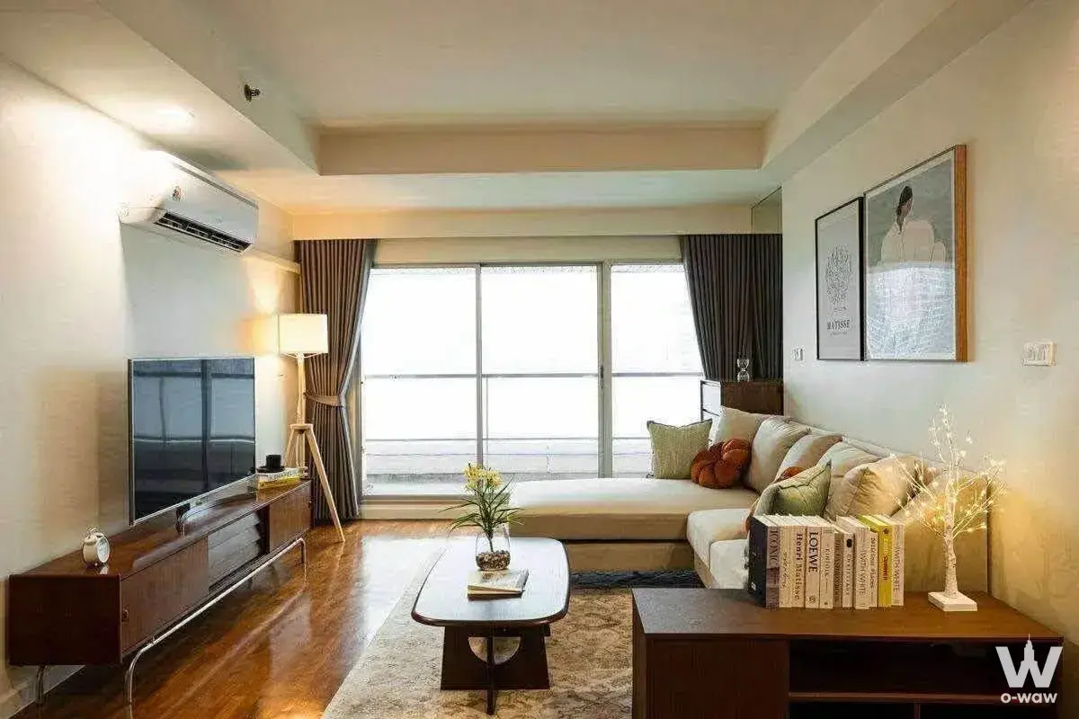 Living room in Baan Nonzee Condominium featuring dark wood floors, L-shaped sofa, and built-in window seat bench