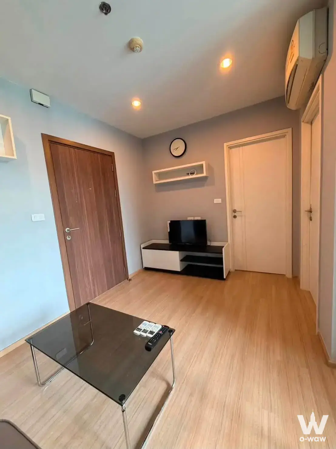 Spacious living room in a 1-bed condo for rent at THE BASE Chaengwattana featuring two-tone walls and a glass-top coffee