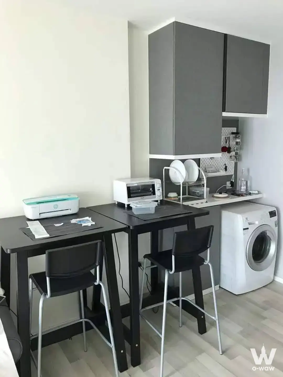 The Key Sathon-Charoen Rat kitchenette with dark counter, bar stools, and under-counter washing machine