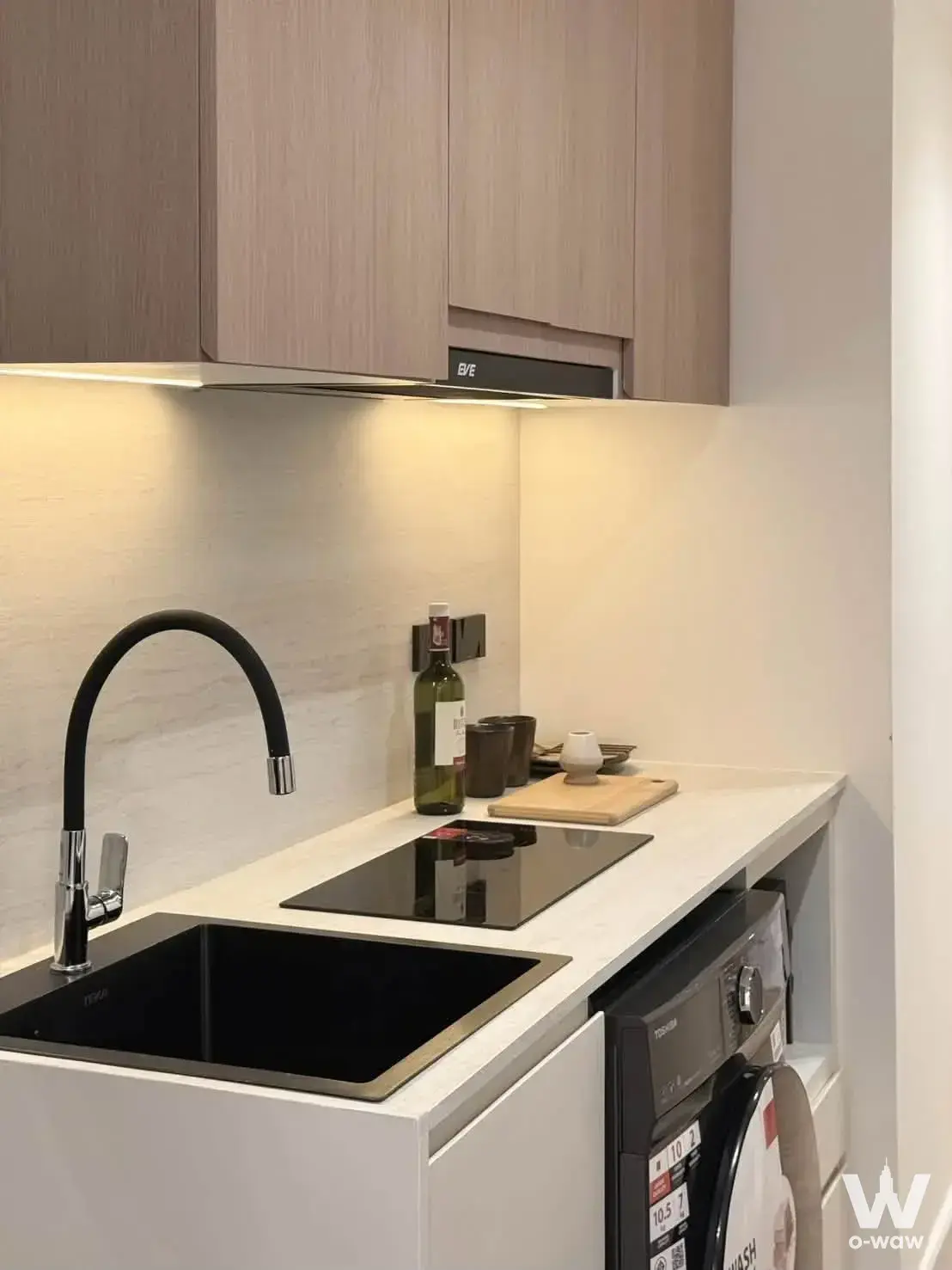The compact kitchenette in a 2-bed Viengping Mansion condo for sale has light wood-grain cabinets and a black glass sink