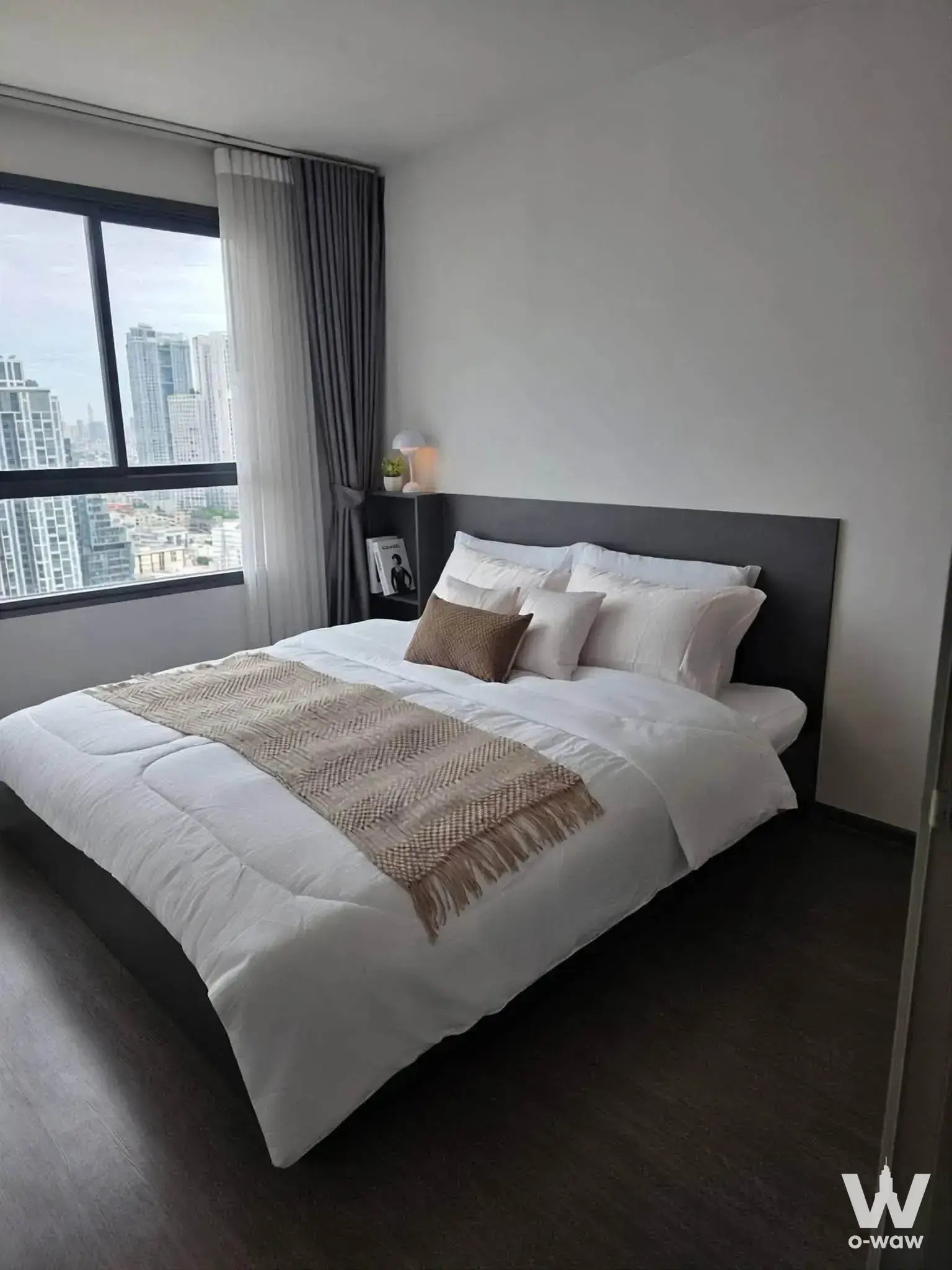 Master bedroom in a 1-bed Ideo Phaholyothin Chatuchak condo with grey bed and city skyline view