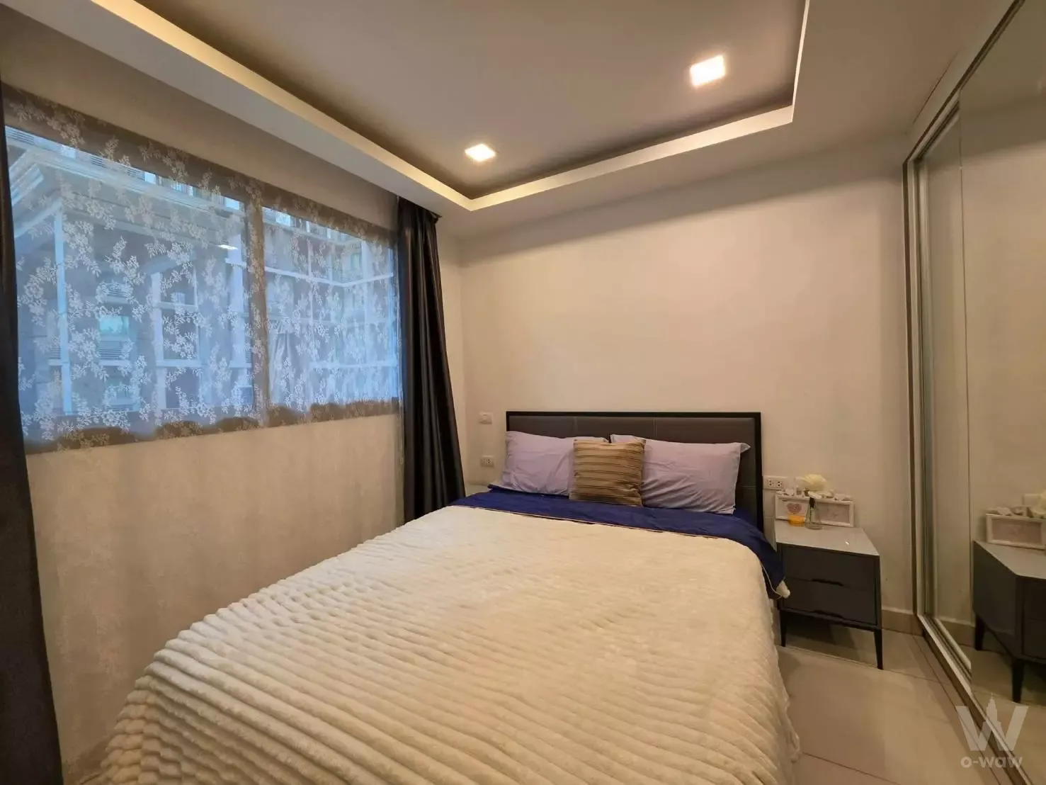 Queen bedroom in Arcadia Beach Continental featuring navy bedding, tray ceiling lighting, and mirrored wardrobe doors