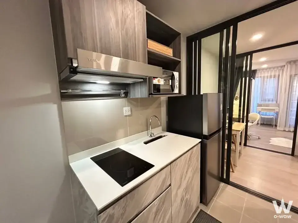 Compact kitchenette in Aspire Onnut Station with quartz counters and a black-framed glass partition
