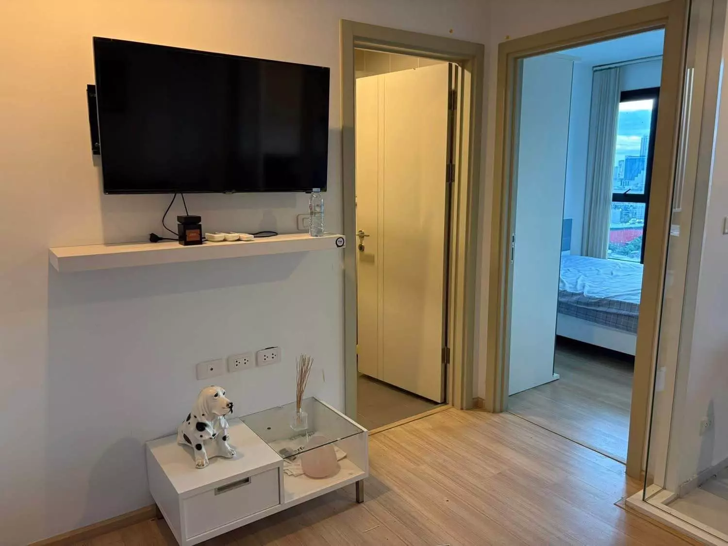 Bright living room in a THE BASE Rama 9 condo showing a TV wall and sliding glass door leading to the bedroom