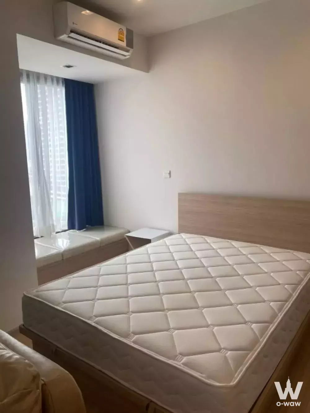 Queen bed with light wood frame and built-in window seat in this 1-bed condo for sale at M Jatujak