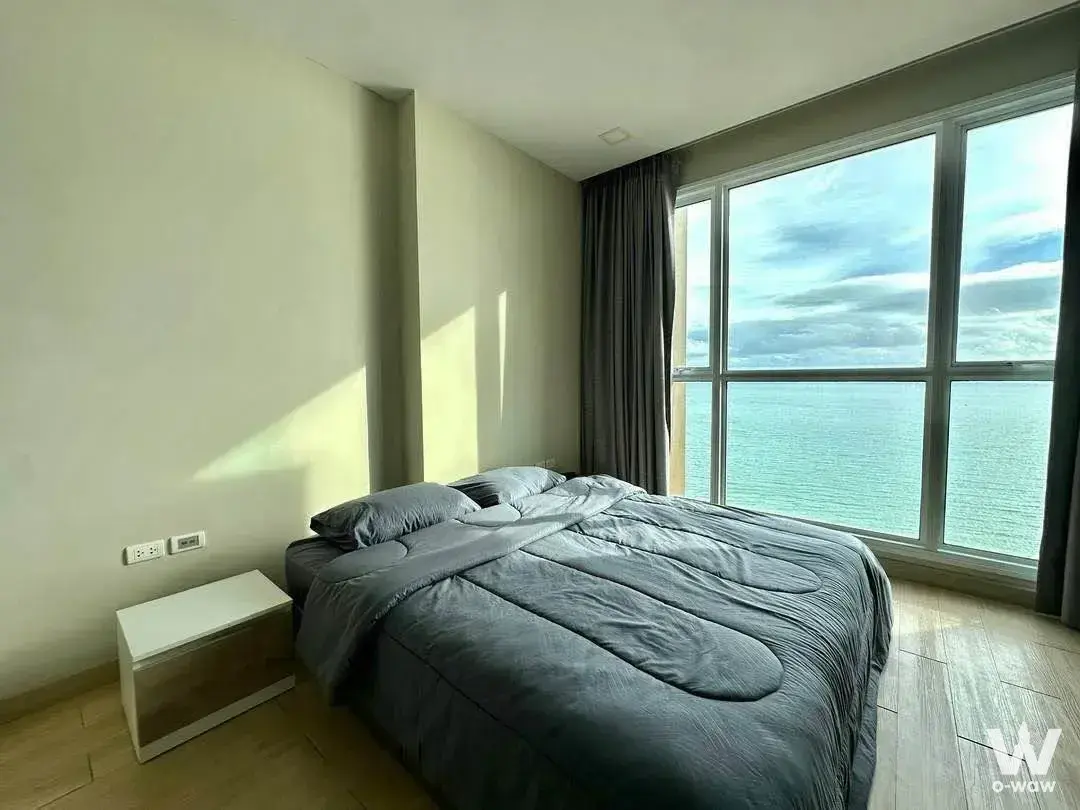 Bright bedroom in Cetus Beachfront Pattaya condo with queen bed and floor-to-ceiling windows framing the ocean view