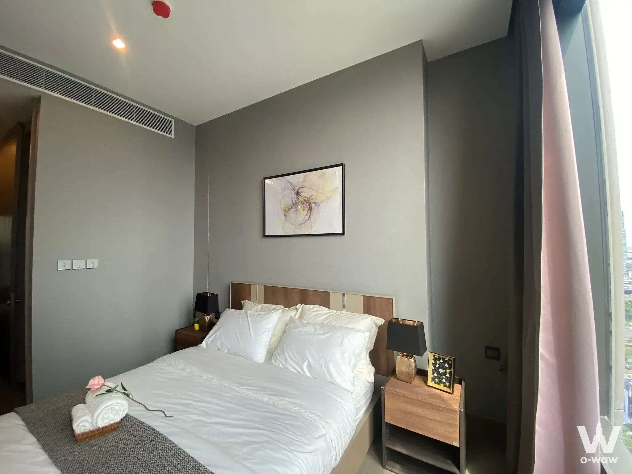 Bright bedroom in a 1-bed condo at THE ESSE with queen bed, wood headboard and floor-to-ceiling city views