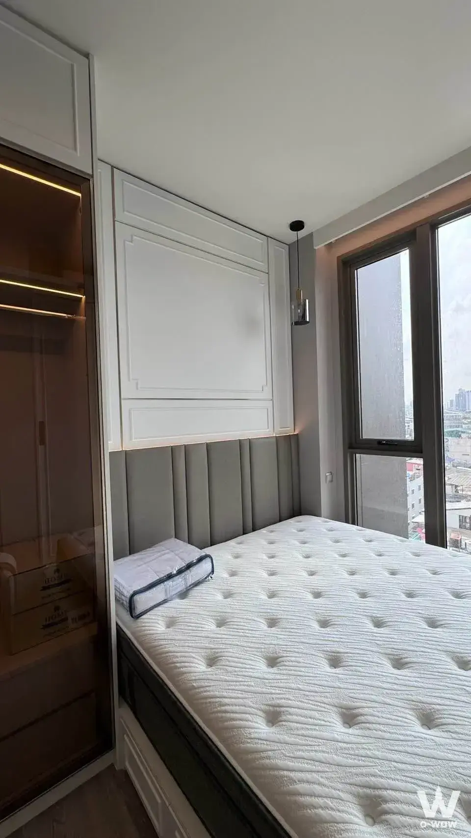 Bedroom in Rhythm Charoenkrung Pavillion featuring grey tufted headboard and glass-front wardrobe