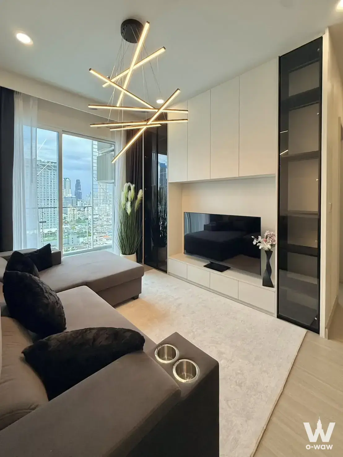 Living room in a 2-bed condo for rent at Premier Condominium, featuring an L-shaped grey sofa and floor-to-ceiling city views