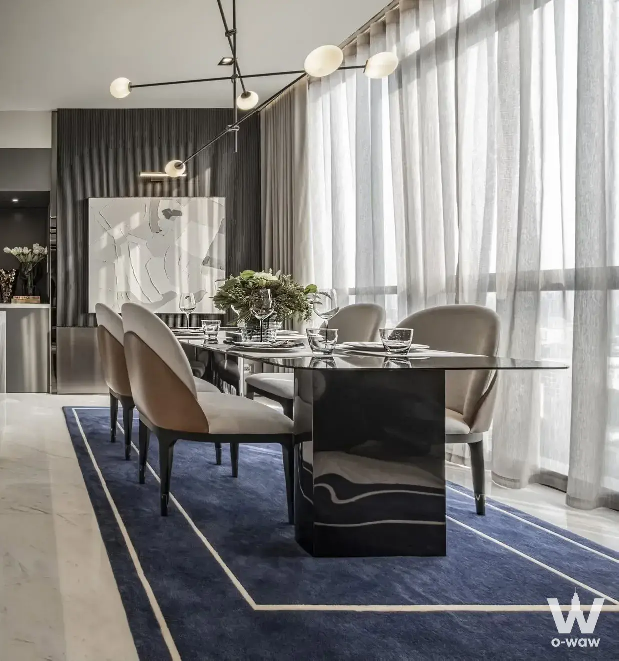 Luxury dining room in The Monument Thong Lo 2-bed condo sale with glass table, navy rug, and feature wall