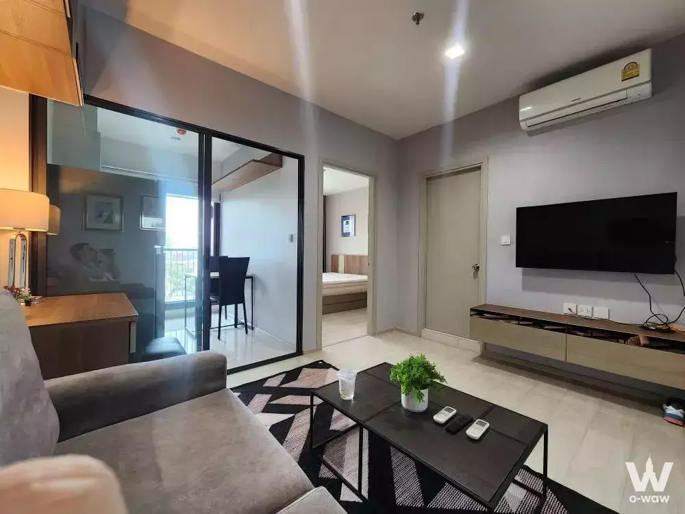 Life Sukhumvit 48 living room with grey fabric sofa and wall-mounted TV in modern neutral tones