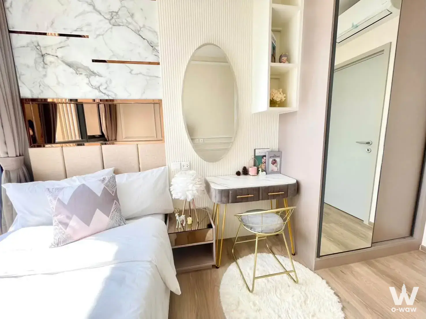 The bedroom in a 2-bed condo for sale at Oka Haus has a queen bed, marble accent wall and vanity desk