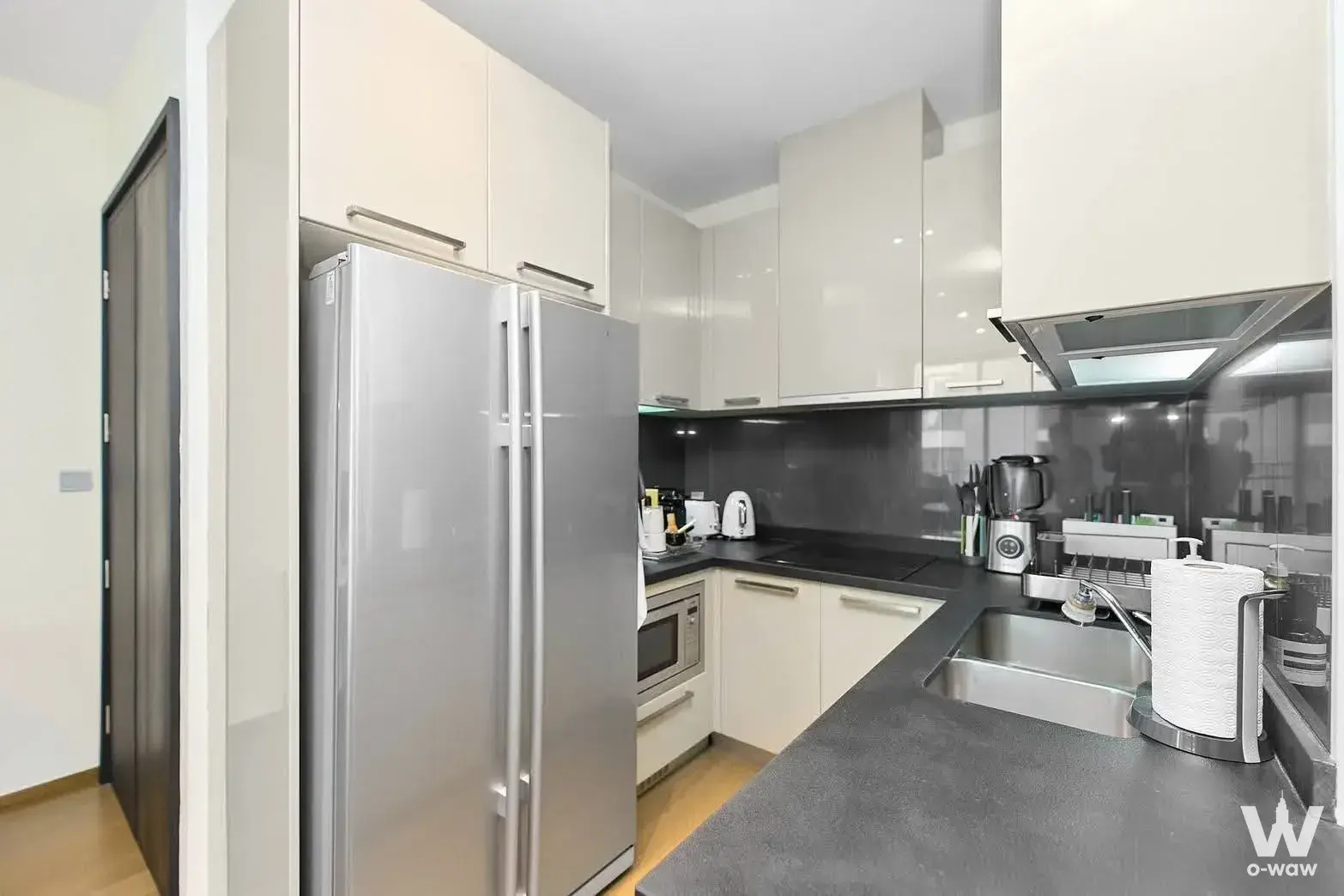 Kitchen in a 1-bed condo for sale in Quattro by Sansiri has cream cabinets, a stainless fridge and dark grey counters