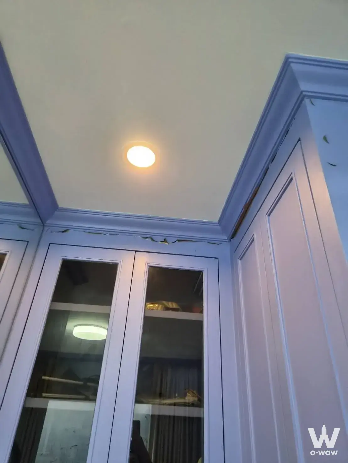 White shaker-style upper cabinets with glass fronts and crown molding in a Supalai Veranda Rama 9 condo