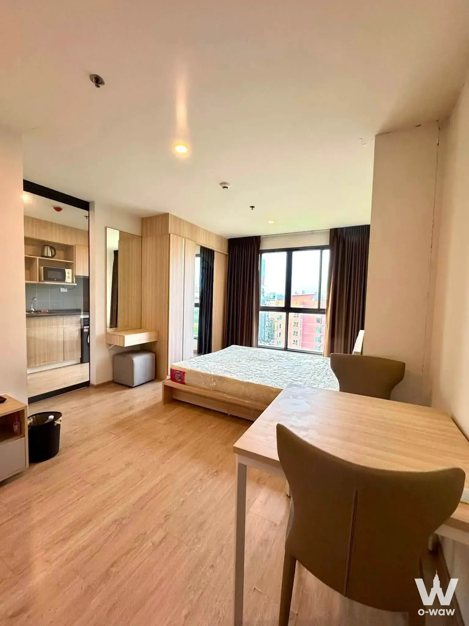 Fully furnished studio with platform bed, dining set, and open kitchen in Ideo O2 1-bed condo for rent
