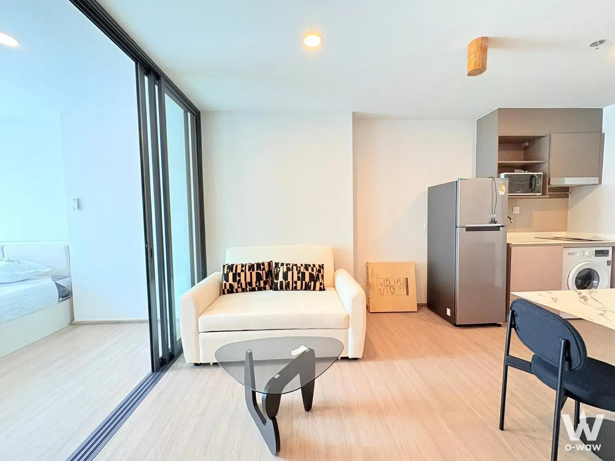 Furnished 1-bed condo in Aspire Sukhumvit-Rama 4 featuring a cream sofa and sliding glass bedroom divider