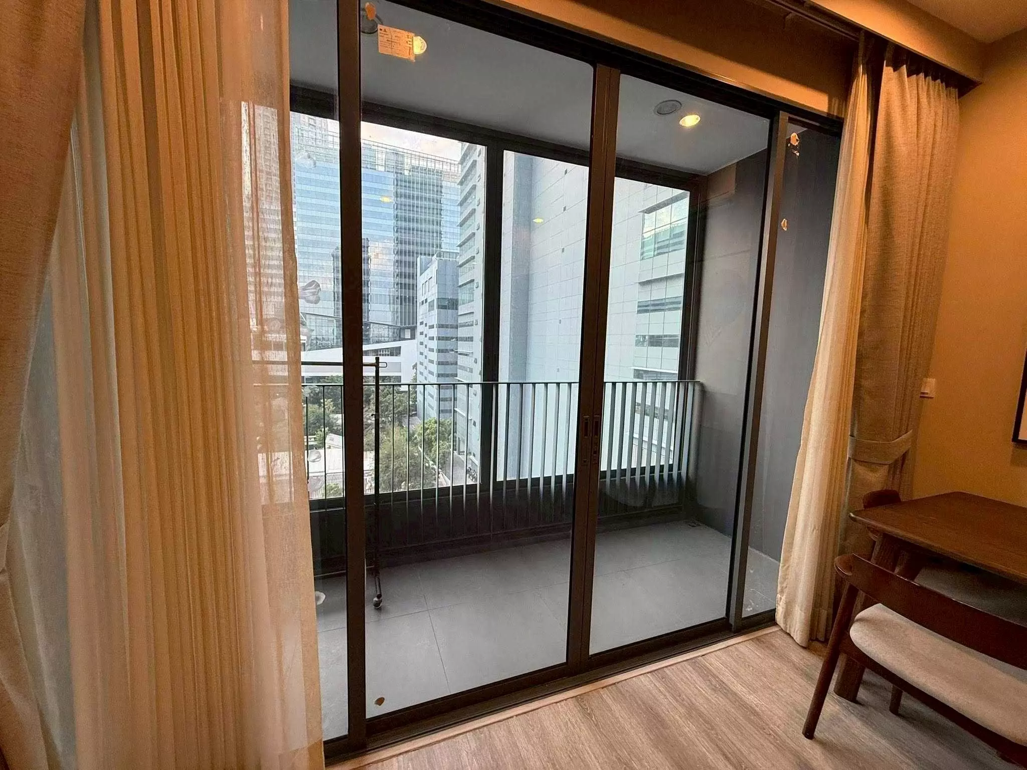 Dining corner with dark wood table and floor-to-ceiling doors opening to a balcony in this Sukhumvit 66 condo
