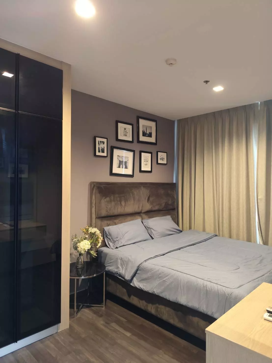 Queen bedroom with taupe velvet headboard and glass side table in this THE LINE Asoke-Ratchada condo for sale