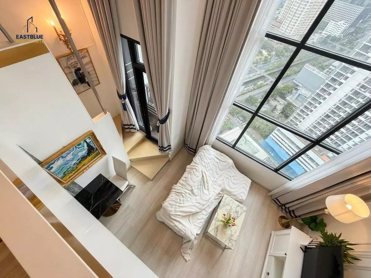 Bright bedroom in KnightsBridge Prime Sathon with floor-to-ceiling skyline views and a mezzanine workspace