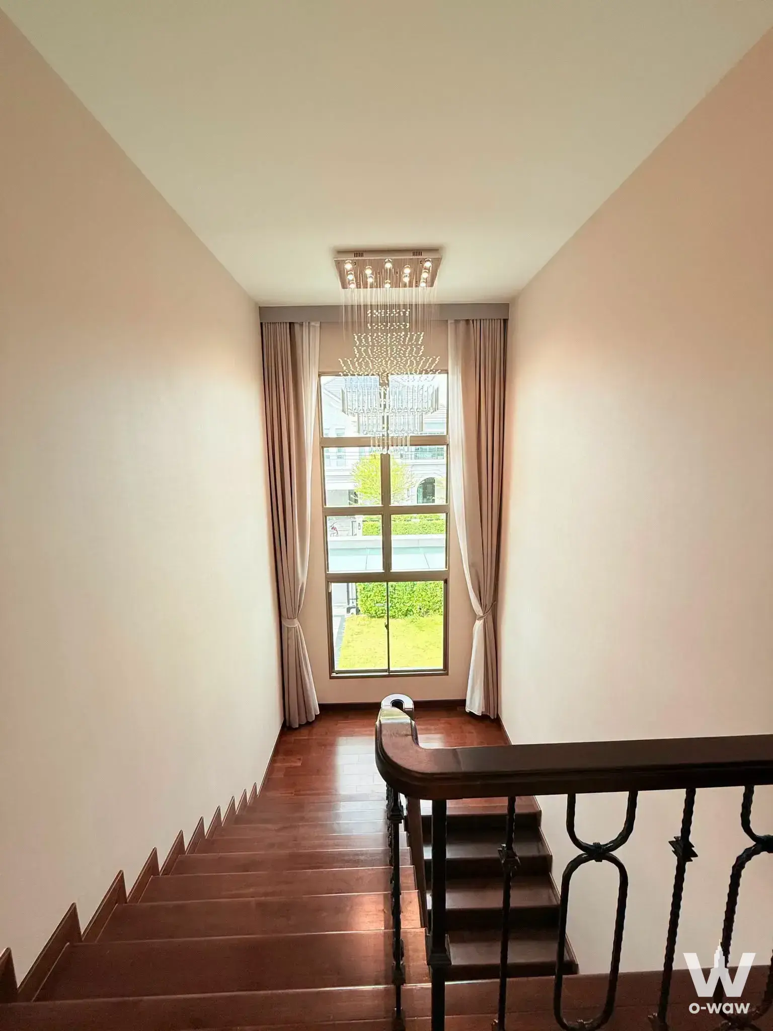 Interior staircase landing in a Perfect Masterpiece house with dark hardwood floors and crystal chandelier