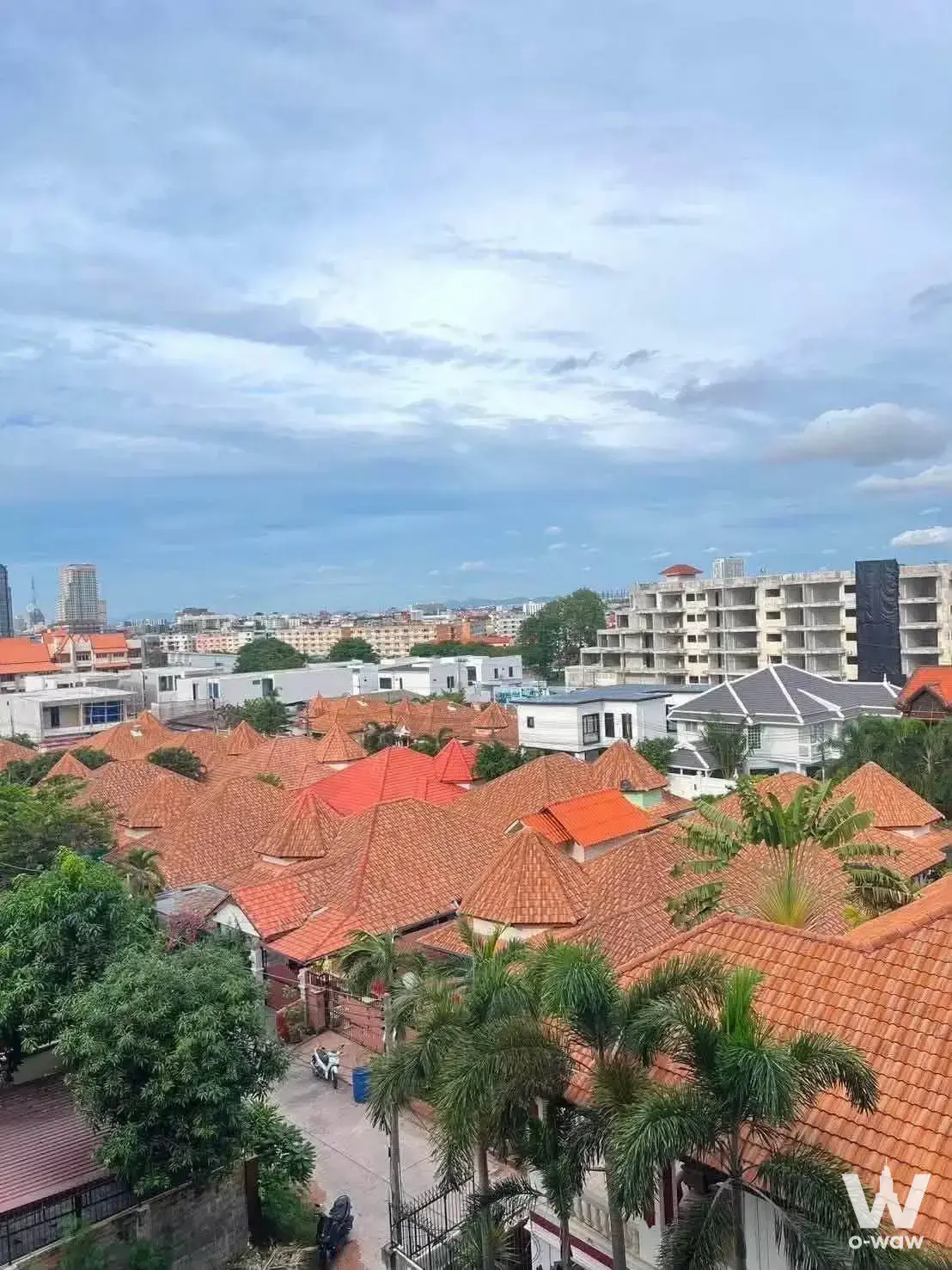 High-floor exterior view from Arcadia Beach Resort showing terracotta roofs, palms, and an unfinished building