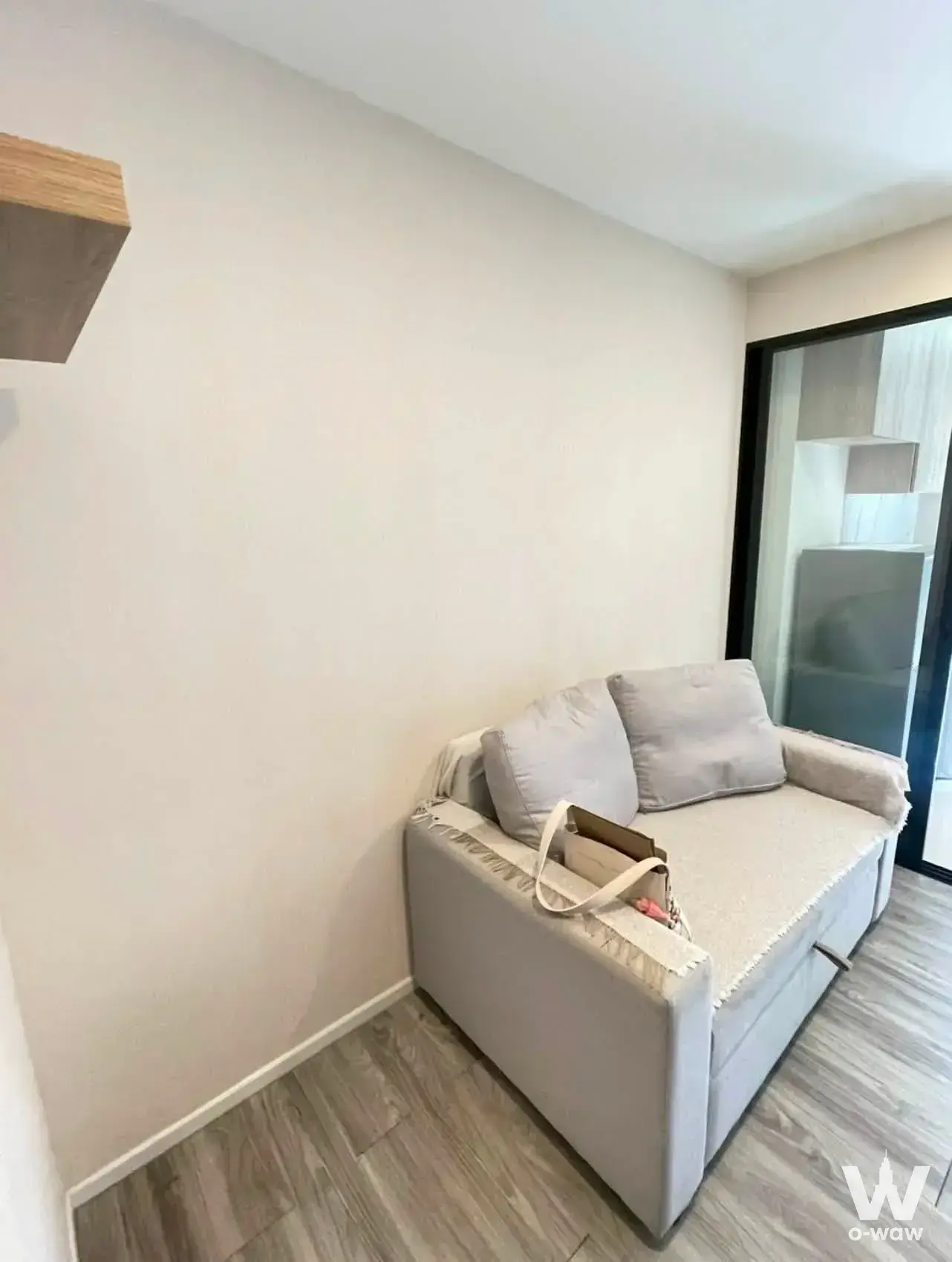 Compact 1-bed condo for sale in IKON Sukhumvit 77 featuring a light-grey sofa and wood-look flooring