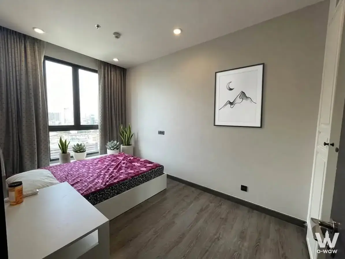 Modern bedroom in a 2-bed URBANO RAJAVITHI condo with a queen bed and city skyline view