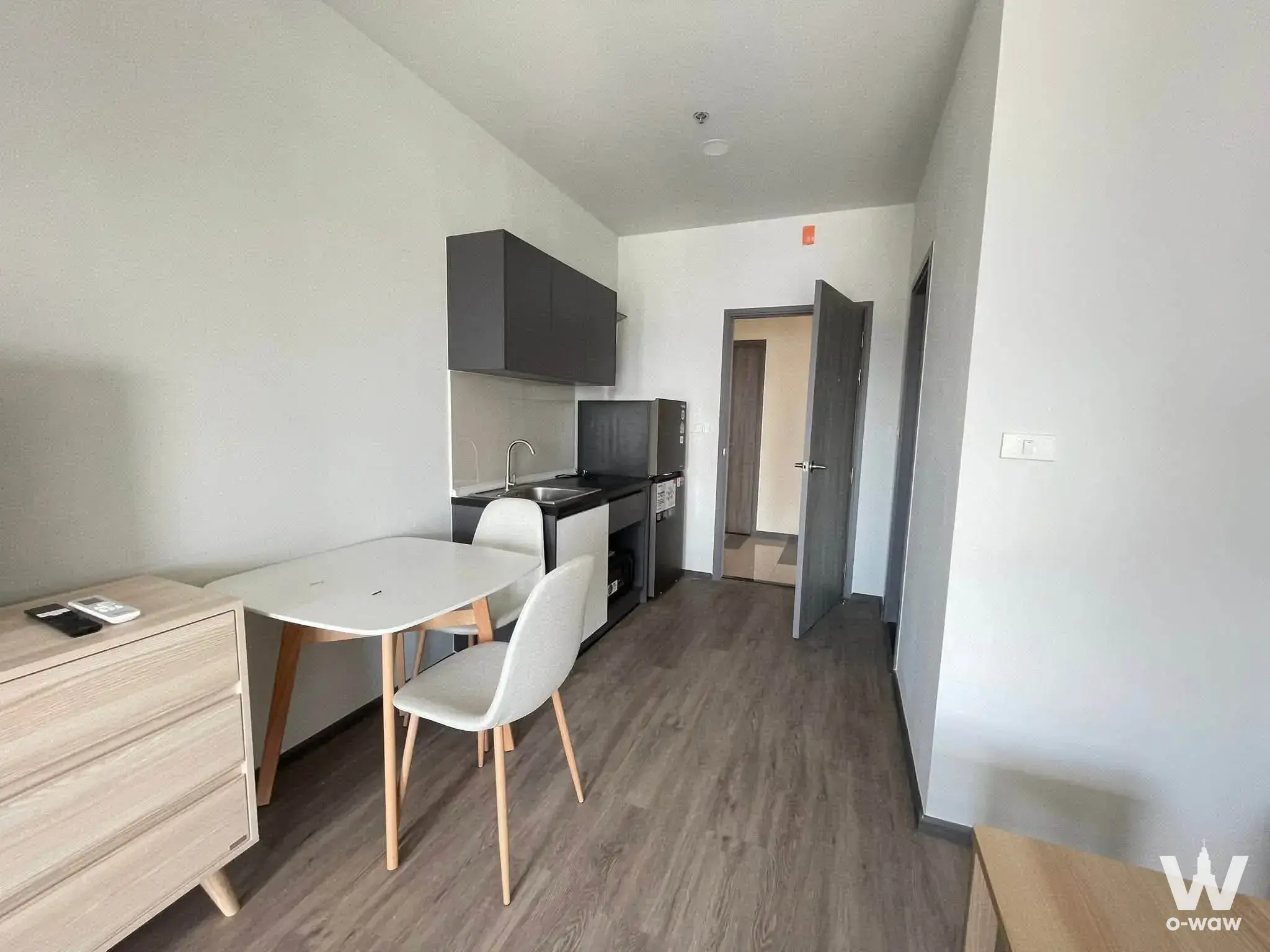 Compact 1-bed condo in Rich Point @BTS Wutthakat with light wood floors and a dark grey kitchenette