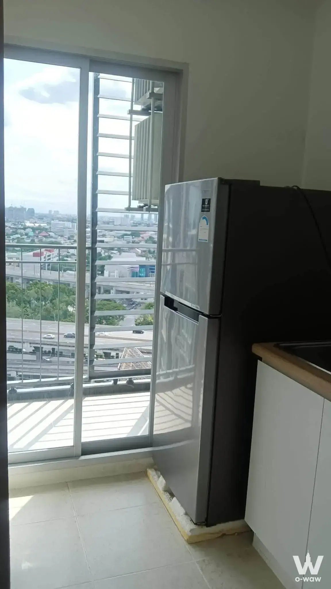 Compact kitchenette with stainless fridge and highway view from a U Delight Rachavibha condo