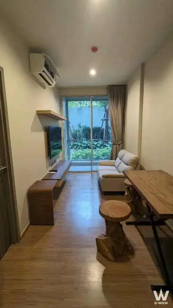 Living room for rent in Q Prasarnmit featuring light oak flooring, garden view balcony, and minimalist furniture
