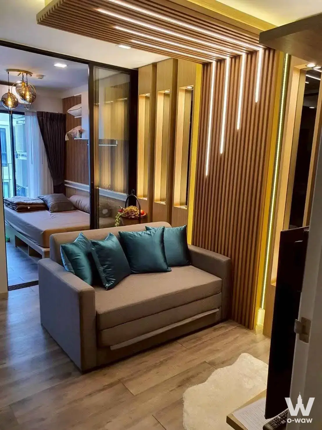 Atmoz Ratchada-Huai Khwang condo interior showing living area separated from bedroom by illuminated wood slat wall